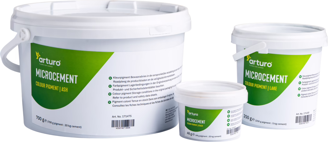 Arturo_Dummy_Microcement_Pigment_2022-11 Trois seaux en plastique blanc de la marque Arturo contenant des pigments pour microciment, photographiés sur fond blanc. Les trois contenants (grand 700 g, moyen 250 g, petit 48 g) présentent une étiquette verte et jaune avec le logo « arturo » et la mention « MICROCEMENT COLOUR PIGMENT », indiquant les teintes Ash, Lake et Beach. On distingue des couvercles emboîtables avec poignées, des informations imprimées sur l'utilisation et le stockage en plusieurs langues, un code-barres et un numéro d'article ; l'éclairage de studio met en valeur la texture mate du plastique et la présentation soignée. Adapté aux fiches produit, à la documentation d'emballage et au commerce en ligne.